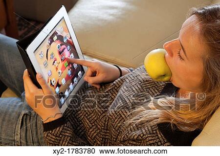 Twelve years old girl relaxing with a tablet computer and with an apple in her mouth View Large Photo Image Stock Image - Twelve years old girl relaxing with a tablet computer and with an apple in her mouth. Fotosearch