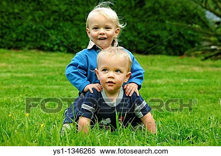 Stock Photography - TWIN BROTHERS PLAYING ON GRASS. Fotosearch