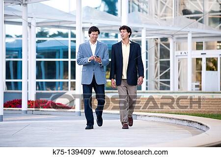 Twin brothers walking outside modern office building View Large Photo Image Stock Photo - Twin brothers walking outside modern office building. Fotosearch