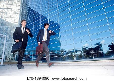 Stock Image - Twin businessmen on the run. Fotosearch