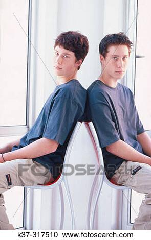 Twin teenage boys sitting in contemporary chairs View Large Photo Image Stock Image - Twin teenage boys sitting in contemporary chairs. Fotosearch