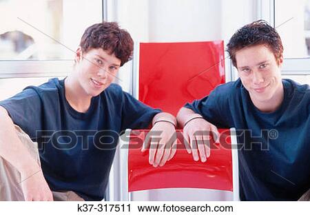 Twin teenage boys sitting next to contemporary chairs View Large Photo Image Stock Image - Twin teenage boys sitting next to contemporary chairs. Fotosearch