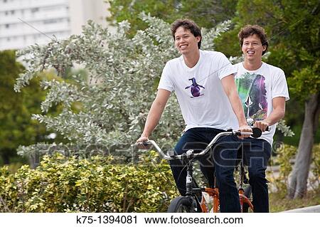 Stock Image - twins riding tandem bike. Fotosearch