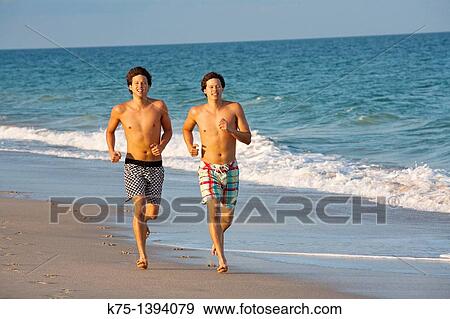 Stock Photo - Twins running on the beach, mixed race, Caucasian father and Chinese-American mother. Fotosearch
