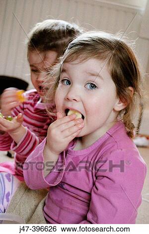 Two 3 year old girls eating fruit, looking into camera View Large Photo Image Stock Photograph - Two 3 year old girls eating fruit, looking into camera. Fotosearch