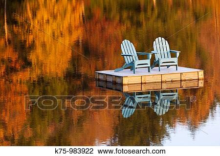Stock Image - two adirondack chairs on dock in autumn. Fotosearch