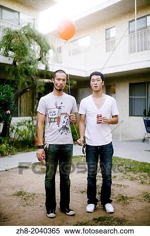Two Asian men holding beers and a balloon in a courtyard in an apartment complex in Los Angeles View Large Photo Image Stock Photography - Two Asian men holding beers and a balloon in a courtyard in an apartment complex in Los Angeles. Fotosearch