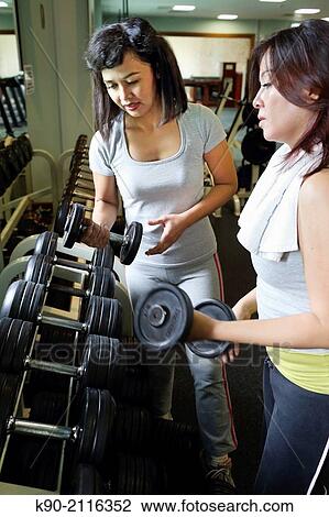 Stock Image - Two asian women choosing the right weight, Jakarta, Indonesia, Southeast Asia.. Fotosearch