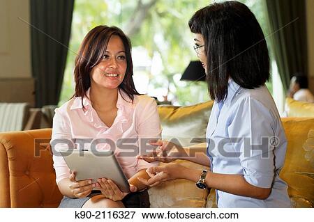 Two asian women holding a tablet computer, Jakarta, Indonesia, Southeast Asia. View Large Photo Image Stock Photo - Two asian women holding a tablet computer, Jakarta, Indonesia, Southeast Asia.. Fotosearch