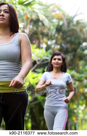Two asian women jogging in the garden behind each other, Jakarta, Indonesia, Southeast Asia. View Large Photo Image Stock Photo - Two asian women jogging in the garden behind each other, Jakarta, Indonesia, Southeast Asia.. Fotosearch