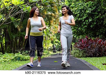 Stock Photography - Two asian women jogging in the tropical garden, Jakarta, Indonesia, Southeast Asia.. Fotosearch