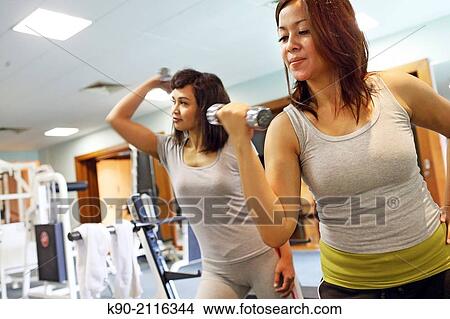 Two asian women lifting a small dumbbell, Jakarta, Indonesia, Southeast Asia. View Large Photo Image Picture - Two asian women lifting a small dumbbell, Jakarta, Indonesia, Southeast Asia.. Fotosearch