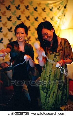 Stock Photo - Two Asian women playing the Nintendo Wii video game system in a loft in Los Angeles. Fotosearch