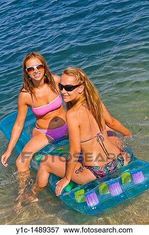 Stock Photo - Two attractive girlfriends are having fun on the beach. Fotosearch