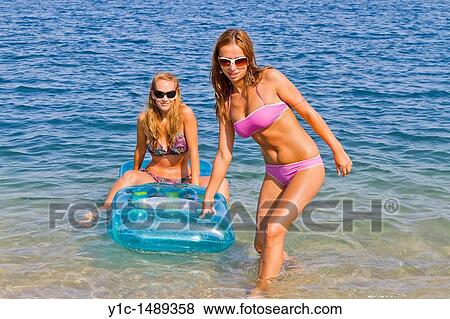 Stock Photo - Two attractive girlfriends are having fun on the beach. Fotosearch