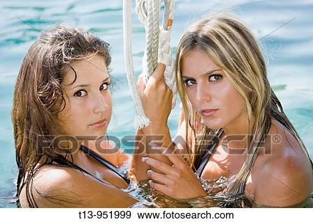 Stock Photo - Two attractive young women in water are holding a rope. Fotosearch