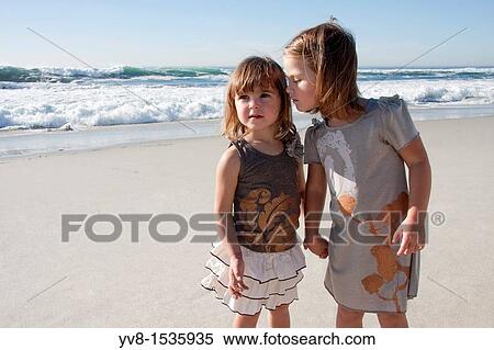 Stock Photography - Two baby girls holding hands at the beach. Fotosearch