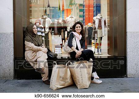 Two beautiful and young moslem ladies sitting in front of the window of a department store, taking a break from a long shopping trip and having their shopping bags in front of them, Oxford Street, London, United Kingdom, Europe View Large Photo Image Picture - Two beautiful and young moslem ladies sitting in front of the window of a department store, taking a break from a long shopping trip and having their shopping bags in front of them, Oxford Street, London, United Kingdom, Europe. Fotosearch
