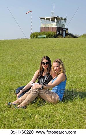 two beautiful sitting on a green meadow in front of a tower for gliders, Salzgitter, Lower Saxony, Germany. View Large Photo Image Stock Image - two beautiful sitting on a green meadow in front of a tower for gliders, Salzgitter, Lower Saxony, Germany.. Fotosearch