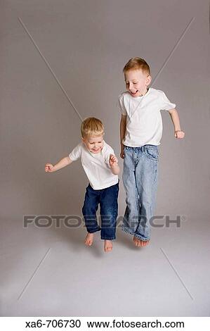 Two blond haired little boyes, aged 6 and 3 years, wearing white t-shirts and blue jeans, smiling and jumping. Studio lighting, grey background. View Large Photo Image Stock Image - Two blond haired little boyes, aged 6 and 3 years, wearing white t-shirts and blue jeans, smiling and jumping. Studio lighting, grey background.. Fotosearch