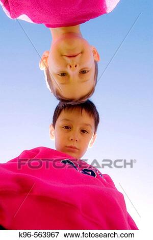 Stock Photo - Two boys head to head looking down at camera. Fotosearch