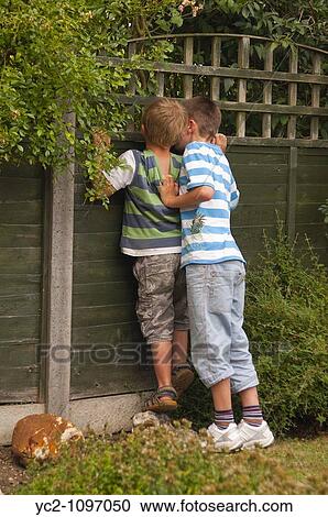 Two boys peering through the fence in the Uk View Large Photo Image Stock Image - Two boys peering through the fence in the Uk. Fotosearch