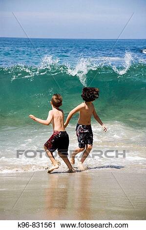 two boys running from a wave View Large Photo Image Stock Image - two boys running from a wave. Fotosearch