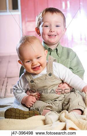 Two brothers, 3 and 1, sitting together smiling View Large Photo Image Stock Photo - Two brothers, 3 and 1, sitting together smiling. Fotosearch