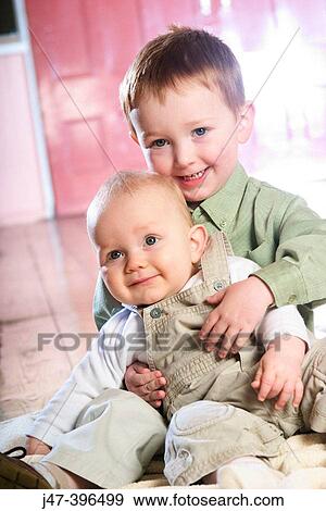 Two brothers, 3 and 1, sitting together smiling View Large Photo Image Stock Photo - Two brothers, 3 and 1, sitting together smiling. Fotosearch