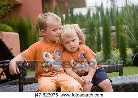 Two brothers, 4 and 2, sitting toether on a chair View Large Photo Image Stock Photography - Two brothers, 4 and 2, sitting toether on a chair. Fotosearch
