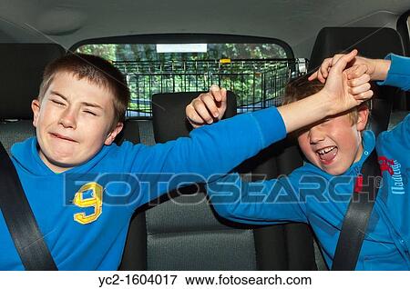 Stock Photo - Two brothers boys children fighting in the car showing the difficulty of driving with kids on board in the Uk. Fotosearch