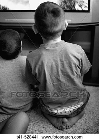 Two brothers sit side by side as they play video games. View Large Photo Image Stock Image - Two brothers sit side by side as they play video games.. Fotosearch