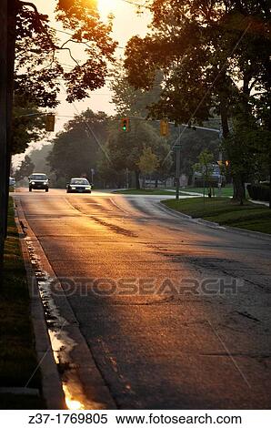 Two cars wait as the traffic light turns green while the eastern sky has a ruddish glow at day break on a gleaming city street in Ontario, Canada View Large Photo Image Stock Photography - Two cars wait as the traffic light turns green while the eastern sky has a ruddish glow at day break on a gleaming city street in Ontario, Canada. Fotosearch