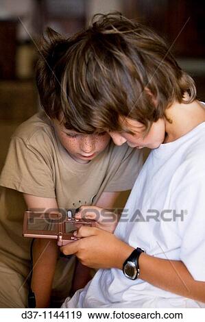Two caucasian boys playing with a video game View Large Photo Image Stock Photo - Two caucasian boys playing with a video game. Fotosearch