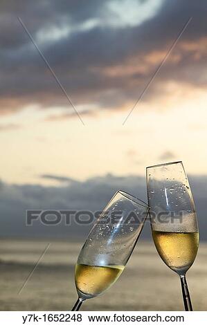 Two champagne flutes toasting against ocean background View Large Photo Image Stock Photo - Two champagne flutes toasting against ocean background. Fotosearch