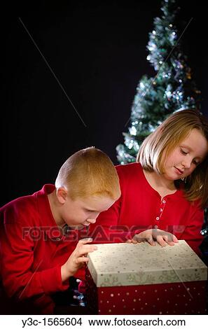 Two children curiously opening a Christmas gift View Large Photo Image Picture - Two children curiously opening a Christmas gift. Fotosearch