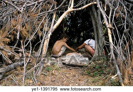 Two children playing inside a hut made from tree branches View Large Photo Image Stock Photography - Two children playing inside a hut made from tree branches. Fotosearch