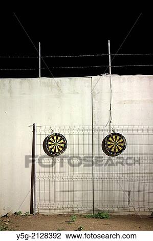 Stock Image - two dart boards on wall outside at night. Fotosearch