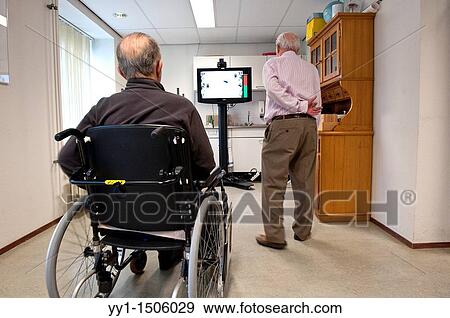 Stock Photo - Two elderly men with stroke rehabilitate in a nursing home in Rotterdam, one of them from his wheelchair.. Fotosearch