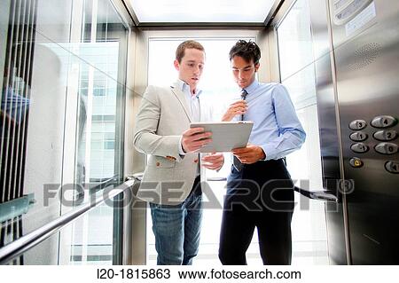 Two executives in elevator, using a digital tablet View Large Photo Image Stock Image - Two executives in elevator, using a digital tablet. Fotosearch