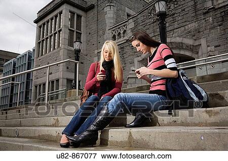Two female college students sitting on the steps of a building texting on the cell phones, University of British Columbia, Vancouver, BC, Canada View Large Photo Image Stock Photo - Two female college students sitting on the steps of a building texting on the cell phones, University of British Columbia, Vancouver, BC, Canada. Fotosearch