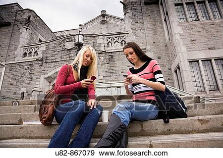 Two female college students sitting on the steps of a building texting on the cell phones, University of British Columbia, Vancouver, BC, Canada View Large Photo Image Stock Photo - Two female college students sitting on the steps of a building texting on the cell phones, University of British Columbia, Vancouver, BC, Canada. Fotosearch
