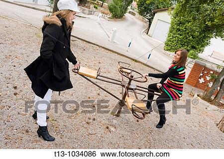 Two female friends on a small carousel View Large Photo Image Stock Photograph - Two female friends on a small carousel. Fotosearch