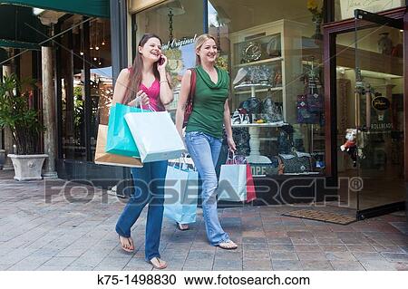 Two friends shopping and talking on cell phone View Large Photo Image Stock Image - Two friends shopping and talking on cell phone. Fotosearch