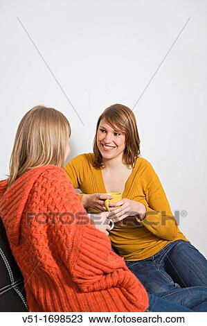 Stock Image - Two girlfriend talking at the sofa. Fotosearch
