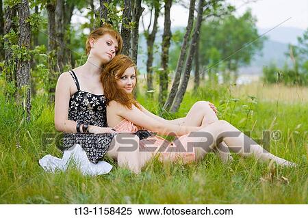 Two girlfriends are sitting on grass View Large Photo Image Stock Photography - Two girlfriends are sitting on grass. Fotosearch