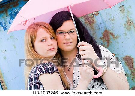 Stock Photograph - Two girlfriends under the pink umbrella. Fotosearch