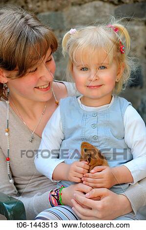 Stock Image - Two girls - 13 and 3 year old - holding Guin? a pig Cavia porcellus France. Fotosearch