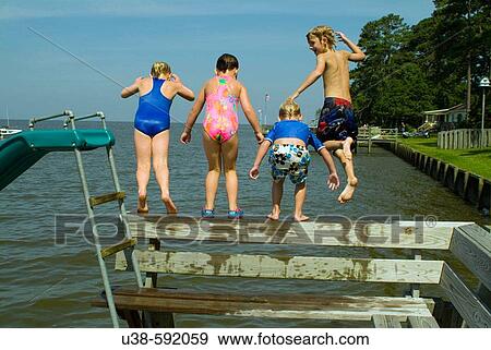 Two girls and two boys jumping into the Albemarle Sound from the dock View Large Photo Image Stock Photo - Two girls and two boys jumping into the Albemarle Sound from the dock. Fotosearch
