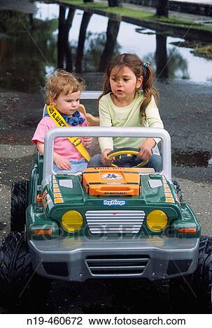 Two girls driving toy automobile View Large Photo Image Stock Image - Two girls driving toy automobile. Fotosearch